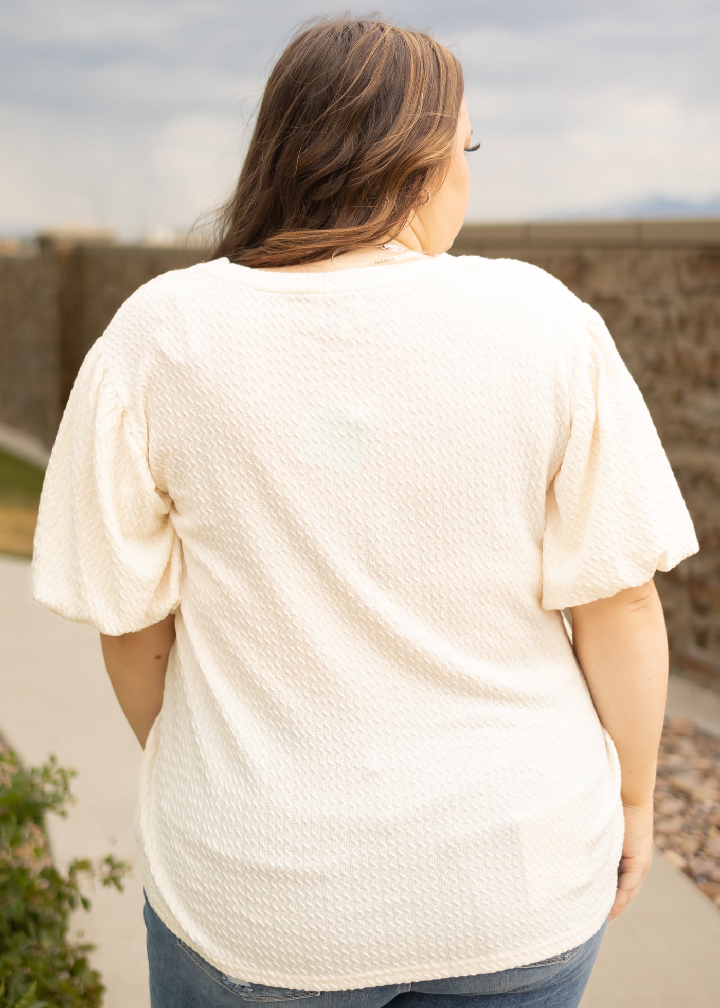 Back view of a plus size cream textured top