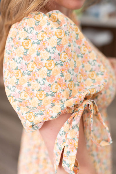 Close up of the tie on the sleeve and the fabric on the peach floral dress