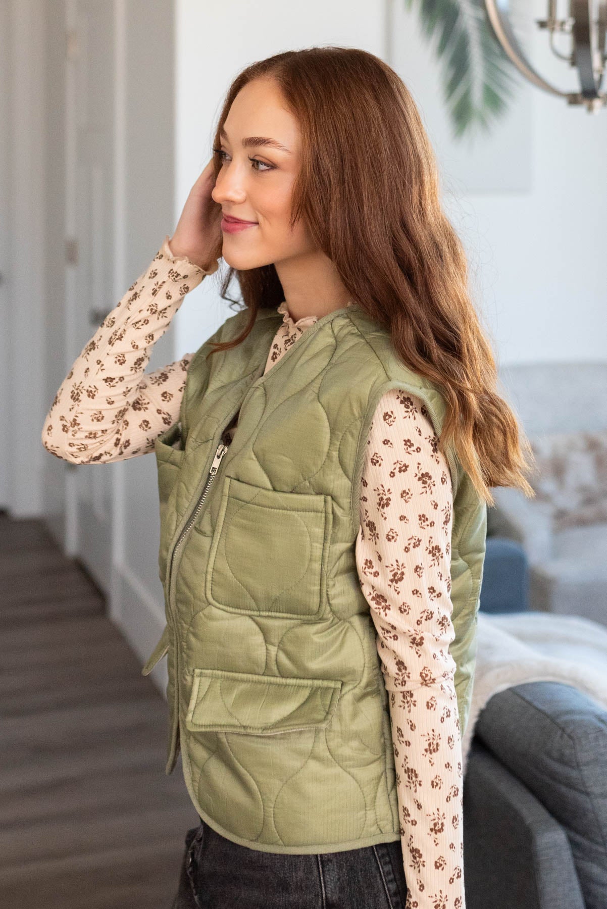 Side view of a olive quilted vest with pockets