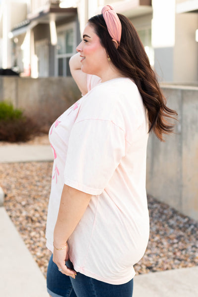 Side view of the plus size light pink ribbon graphic tee
