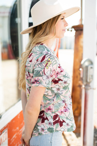 Side view of a short sleeve pink floral top that buttons up and has a v-neck.