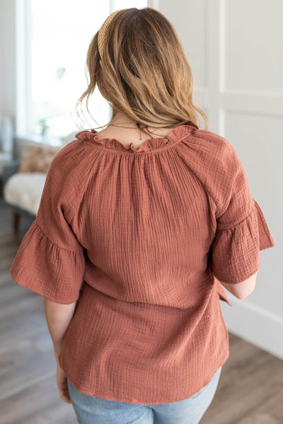 Back view of the terracotta blouse with a ruffle at the neck