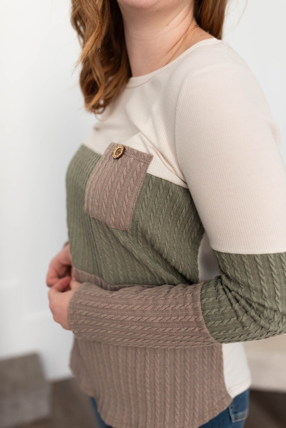 Side view of the olive pocketed cable knit top