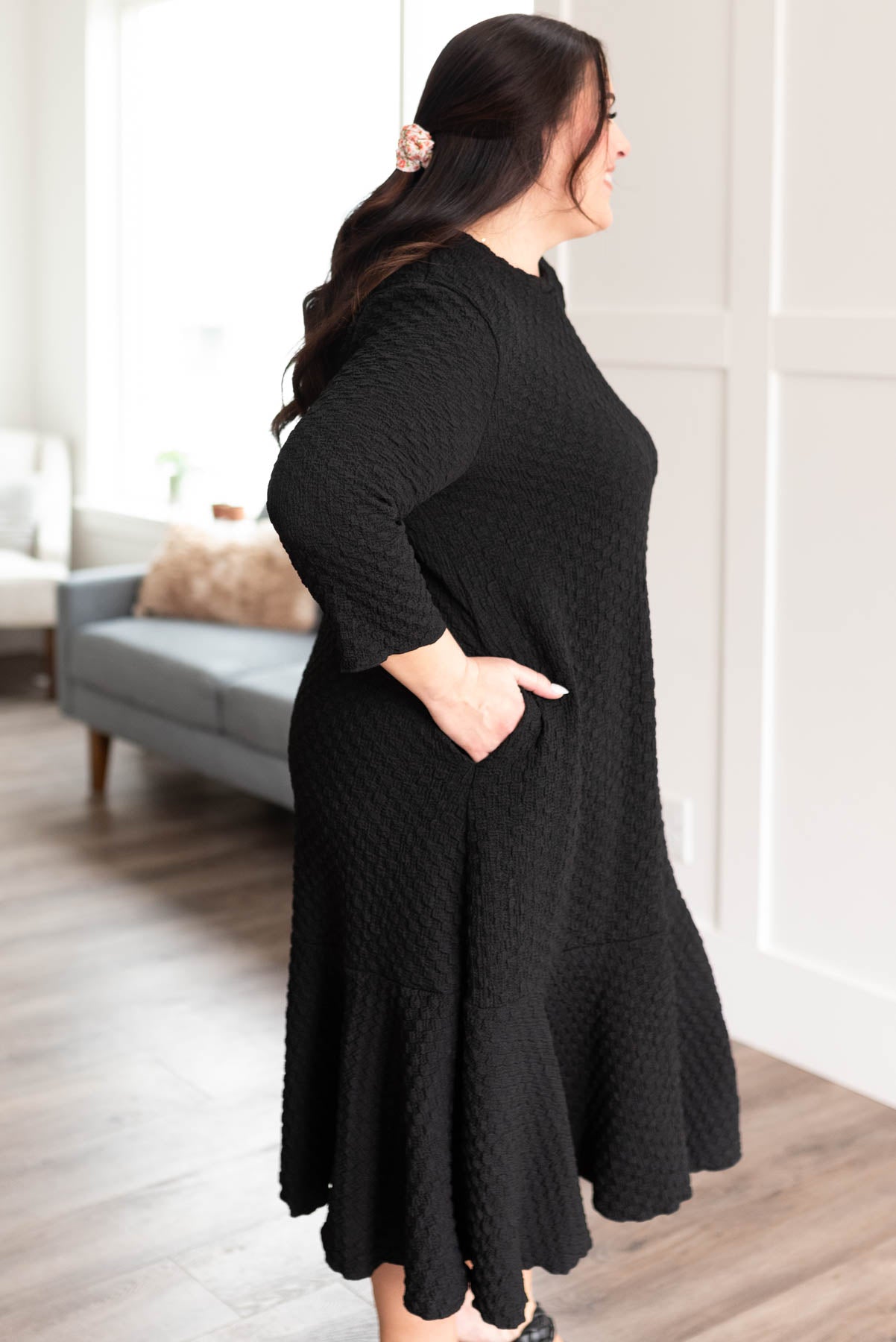Side view of the plus size black textured ruffle hem dress