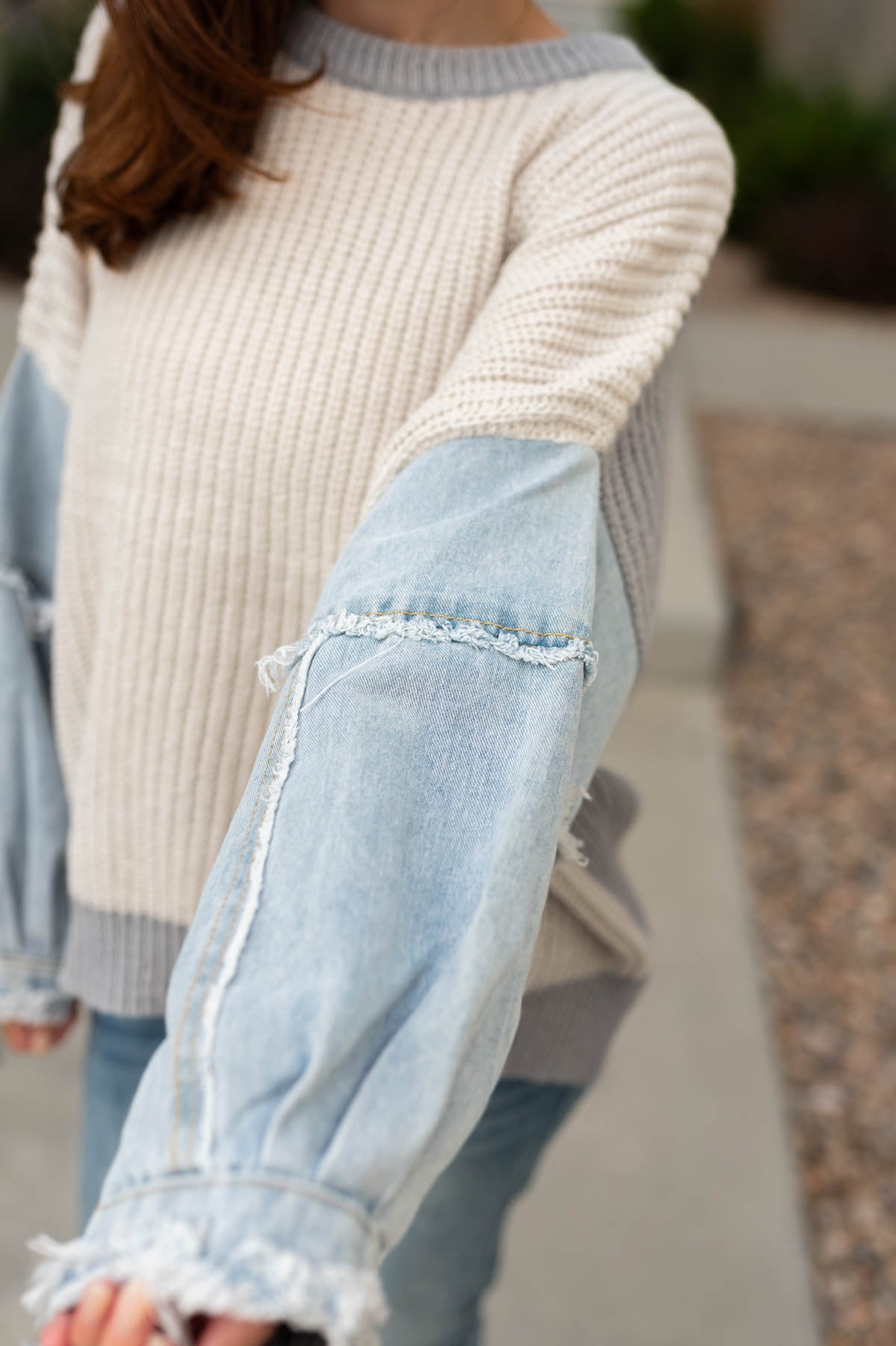 Denim sleeve view of a grey sweater