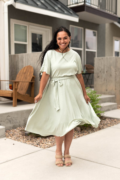 Below the knee plus size sage dress with a full skirt that ties in front