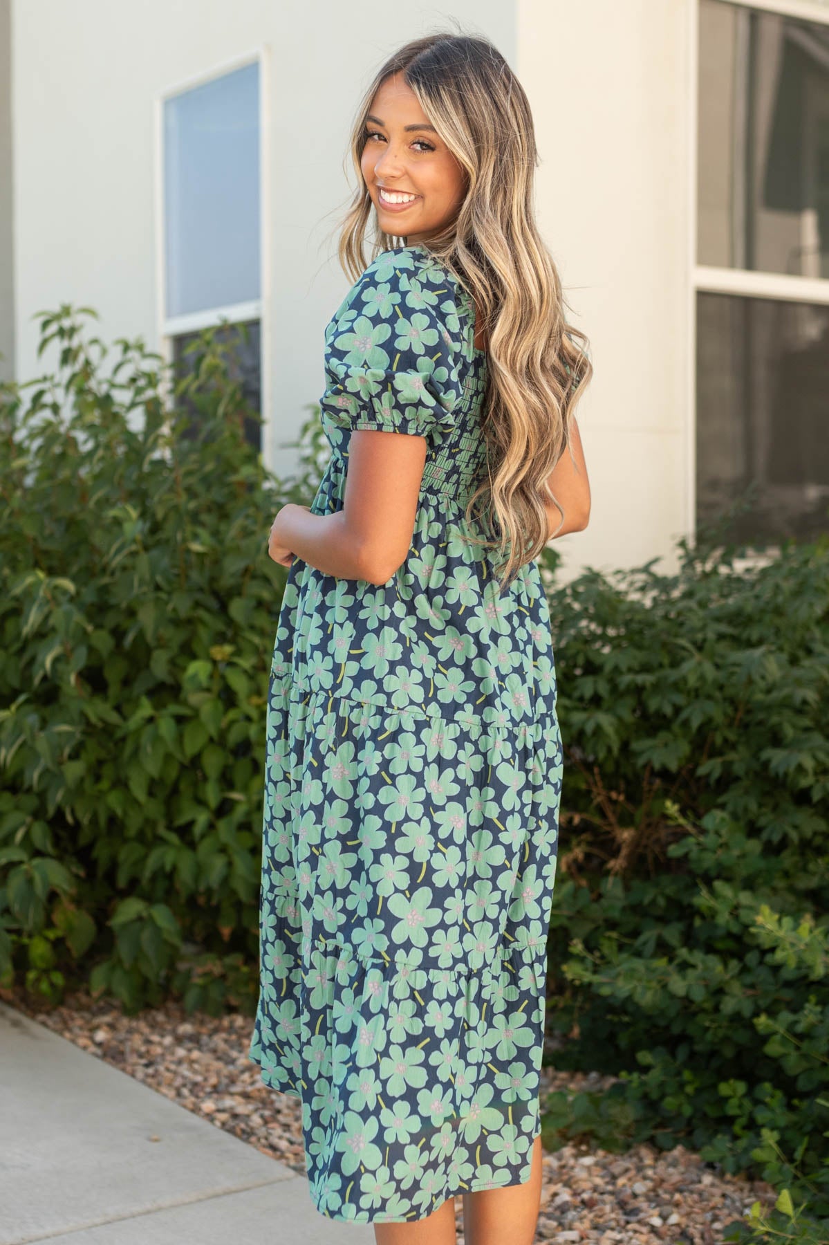 Side view of a short sleeve dark green dress with floral print