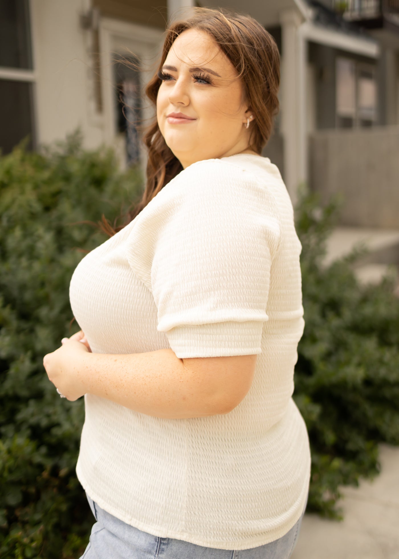 Side view of a plus size cream top with short sleeves