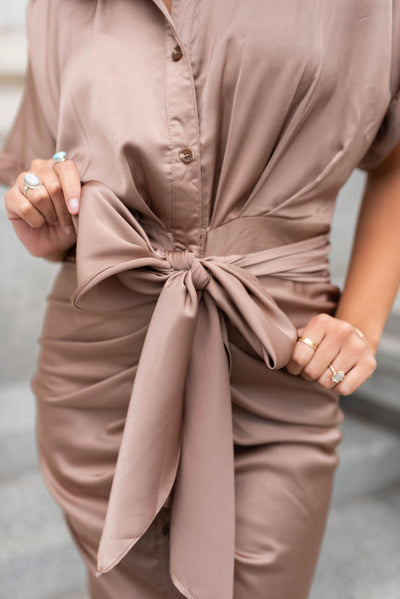 Close up of the bow and the rushing on the skirt of a mocha satin dress