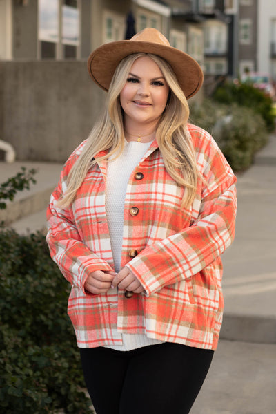 Front view of a button up coral plaid shacket with a collar