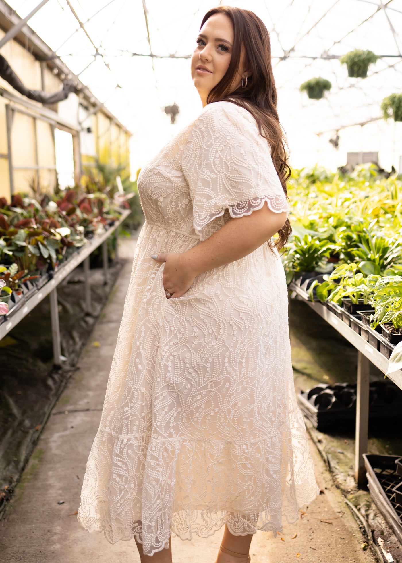 Side view of a plus size lace cream dress with short sleeves and pockets