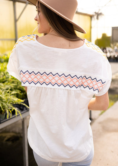 Back view of a white top with cross stitching on the back