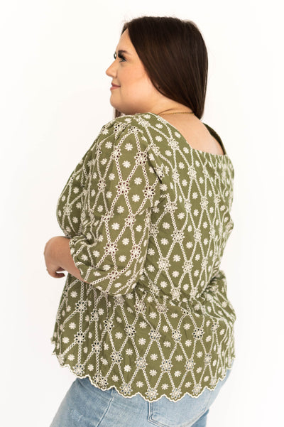 Side view of a plus size floral olive top with cream embroidery