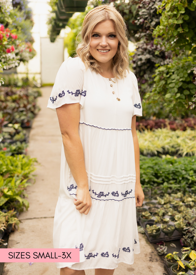 Side view of a short sleeve white dress with blue embroidery