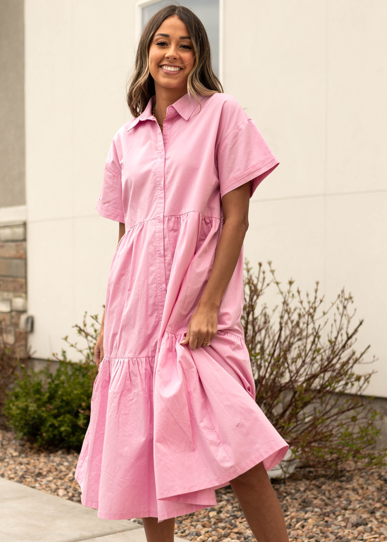 Front view of a strawberry milk pink button up dress with a collar