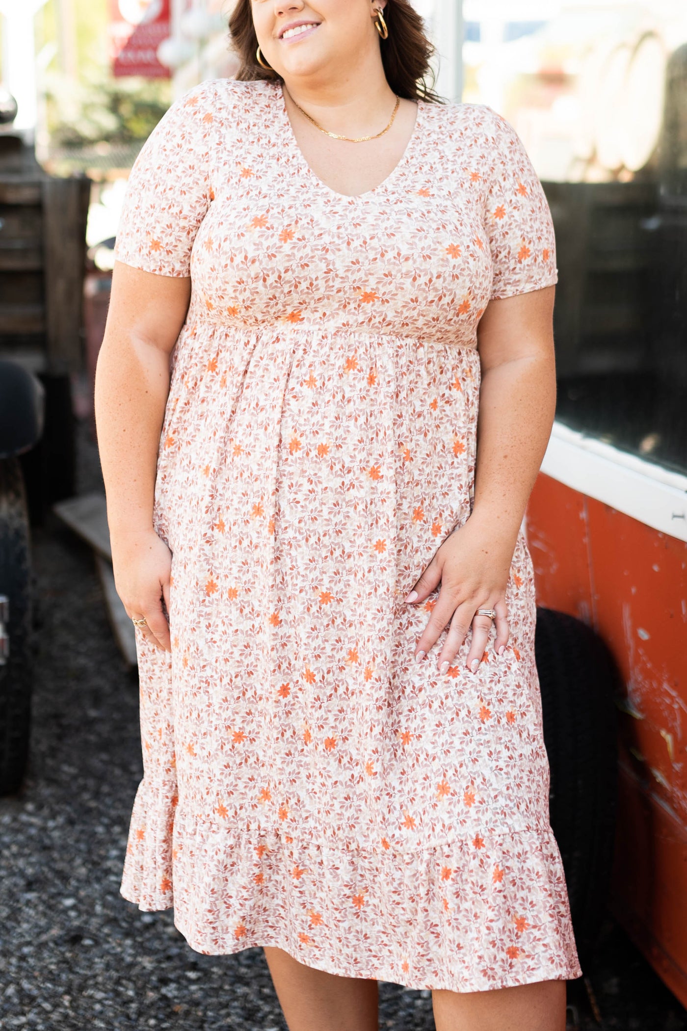 Side view of a plus size taupe floral dress with a ruffle at the hem