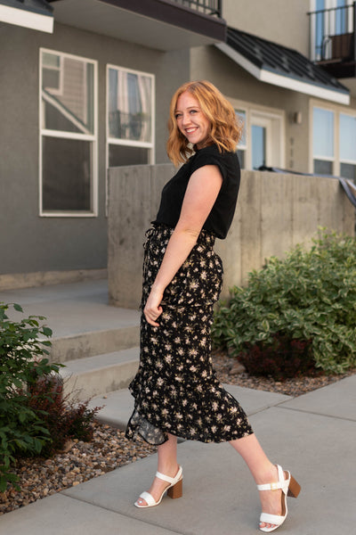 Side view of a black top with floral skirt that are sold separately