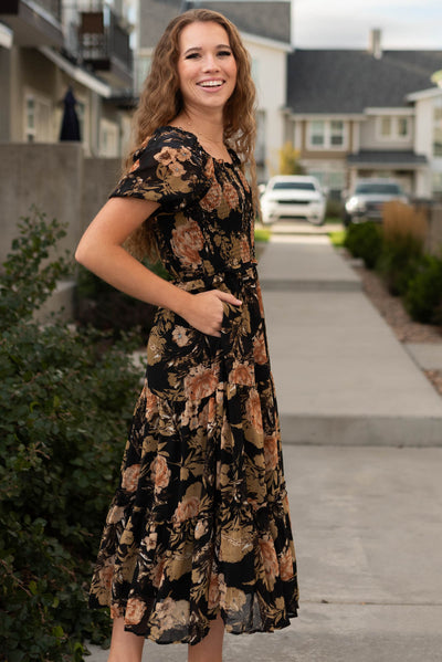 Side view of a black floral dress with pockets