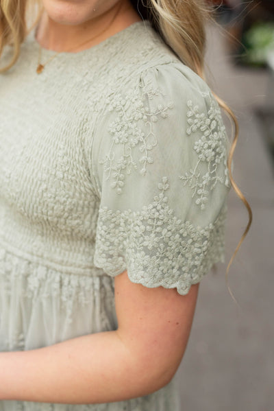 Close up of the sleeve and embroidered fabric of the sage embroidered dress