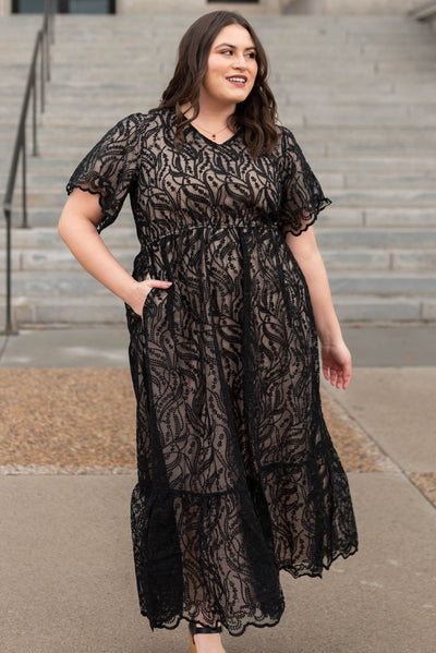Front view of a plus size lace black dress with a nude lining