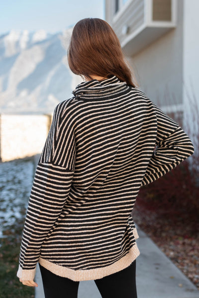 Back view of a black turtle neck sweater with cream stripes