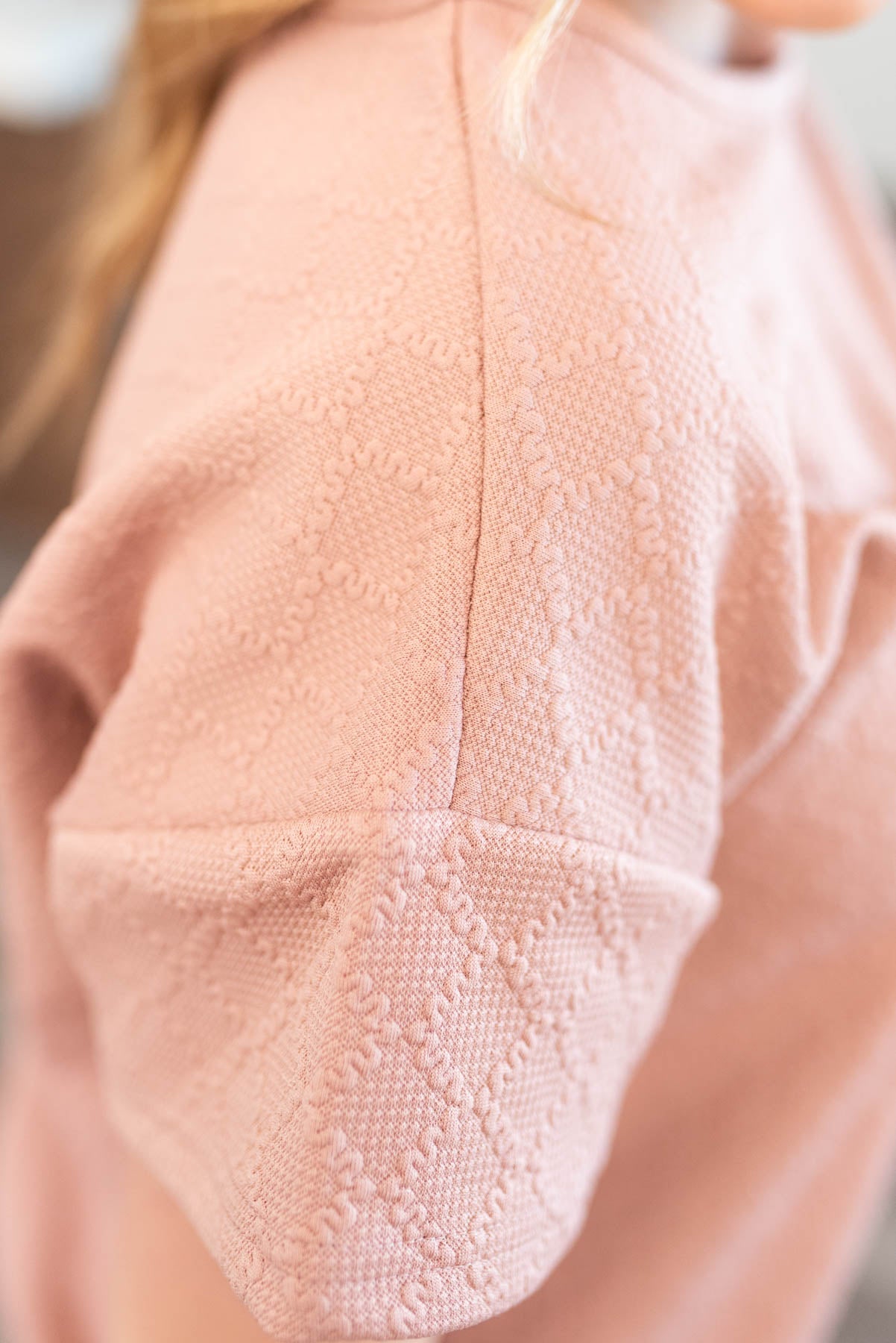 Close up of the fabric pattern on the dusty pink textured top