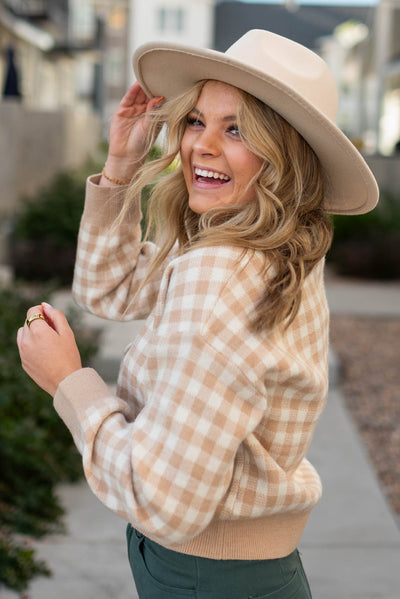 Side view of a taupe checkered button cardigan