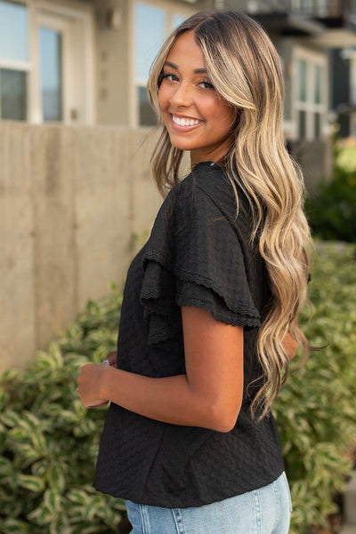 Side view of a black top with ruffle sleeves