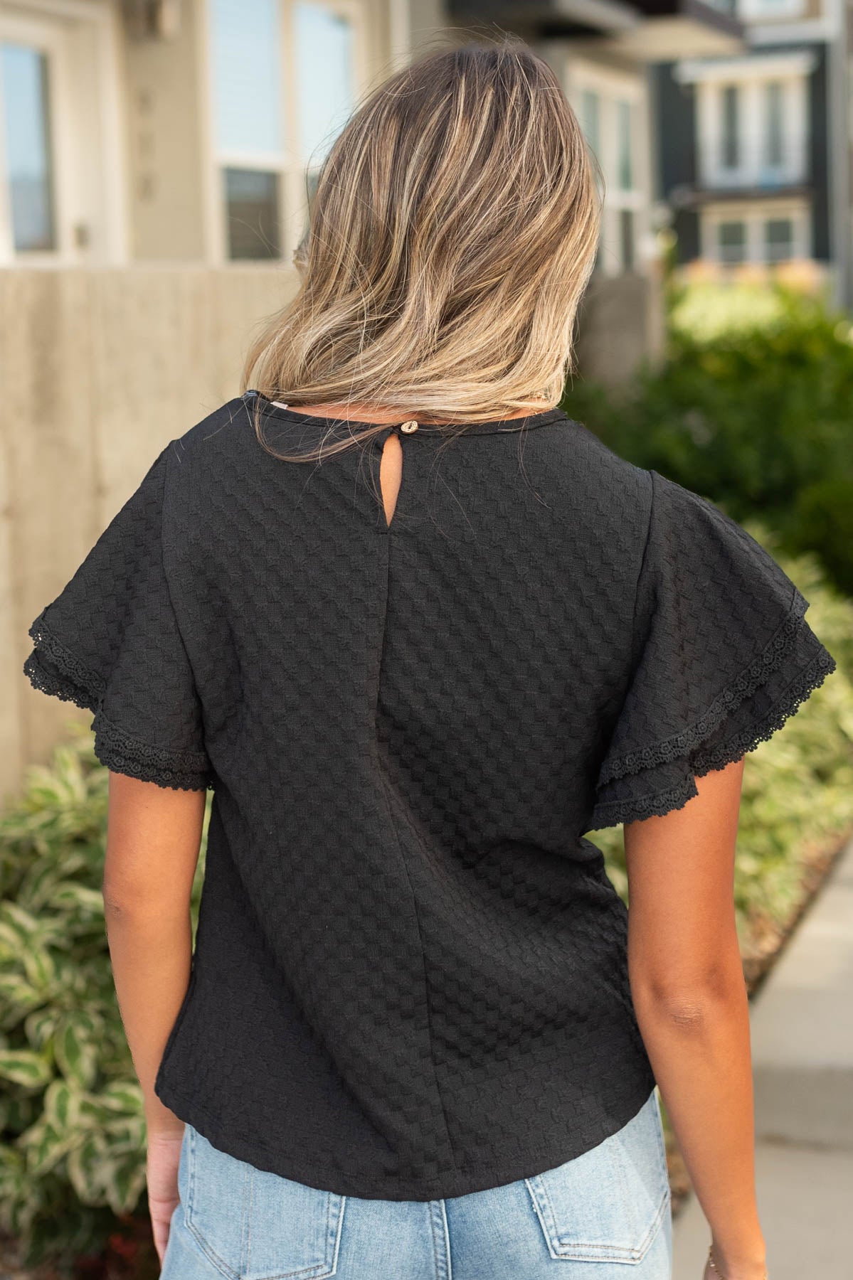 Back view of a black top with a button closer