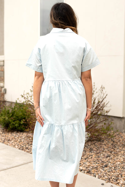 Back view of a short sleeve blue button up dress with a collar