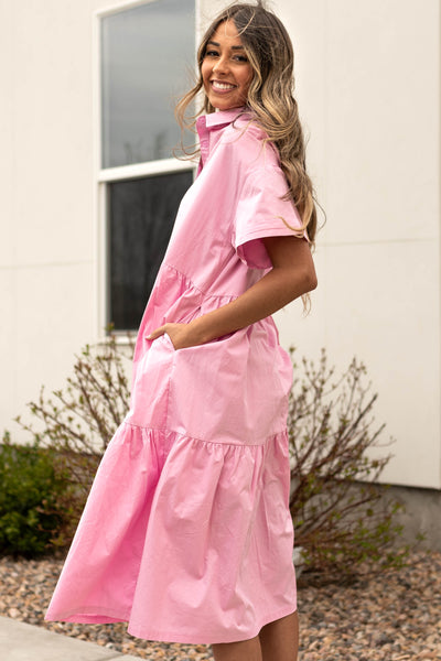 Side view of a strawberry milk pink dress that buttons up and has a collar