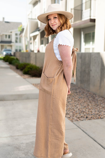 Side view of a taupe wide leg jumpsuit that tie in back