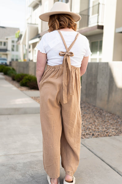 Back view of a taupe wide leg jumpsuit with pocket and tie in back