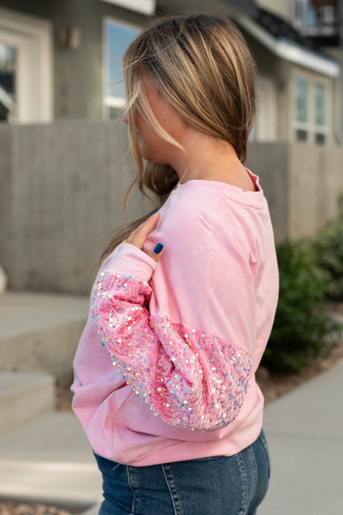 Side view of a pink pullover top with sequence sleeves