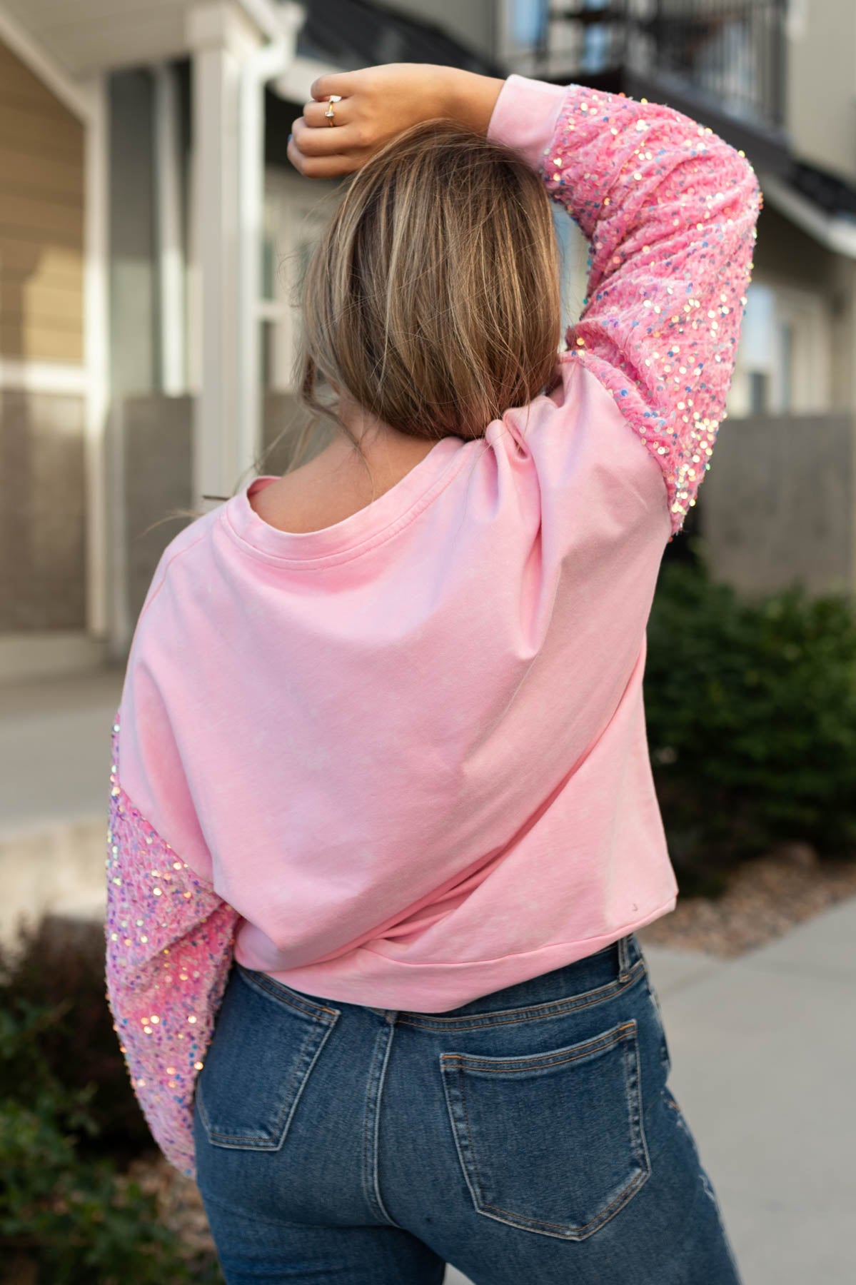 Back view of a pink pullover with sequence sleeves