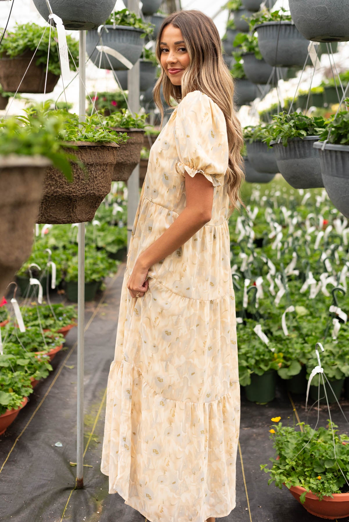 Side view of the tan pattern tiered dress with a floral pattern