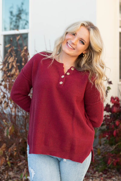 Buttons at the neck on a long sleeve burgundy sweater