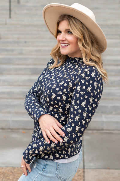Side view of a navy flower print long sleeve top with white flowers