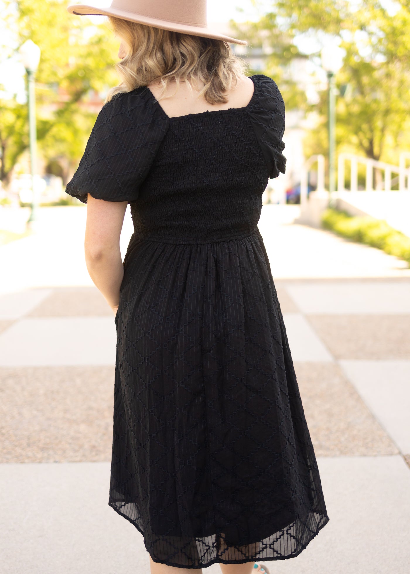 Back view of a short sleeve black dress with smocked bodice