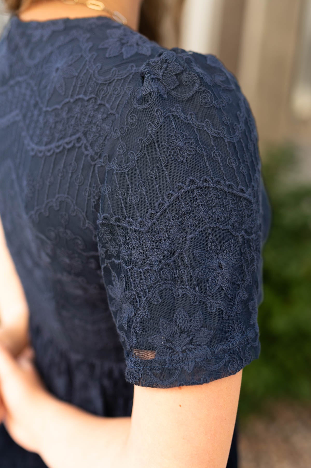 Close up view of a navy lace dress sleeve