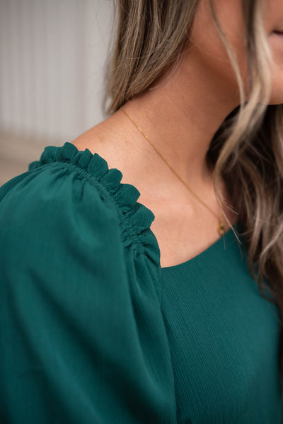 Close up of the sleeve and neckline of a green ruffle tiered dress