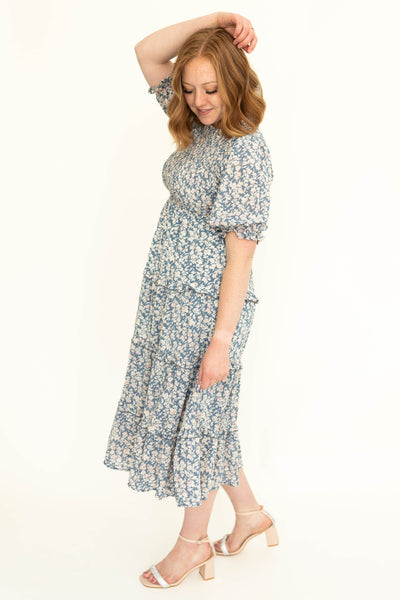 Side of a short sleeve blue floral tiered dress.