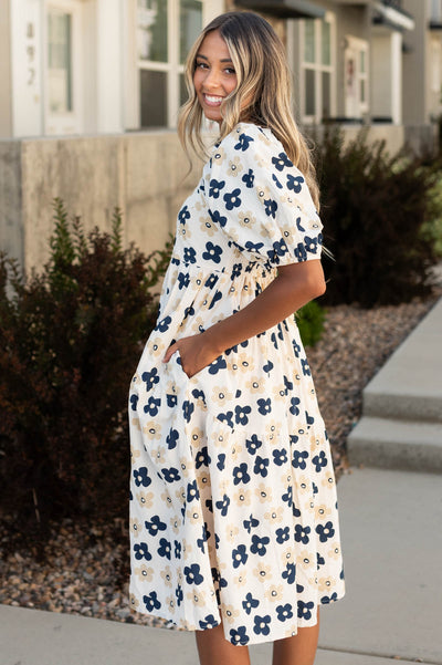 Side view of a cream floral dress with pockets