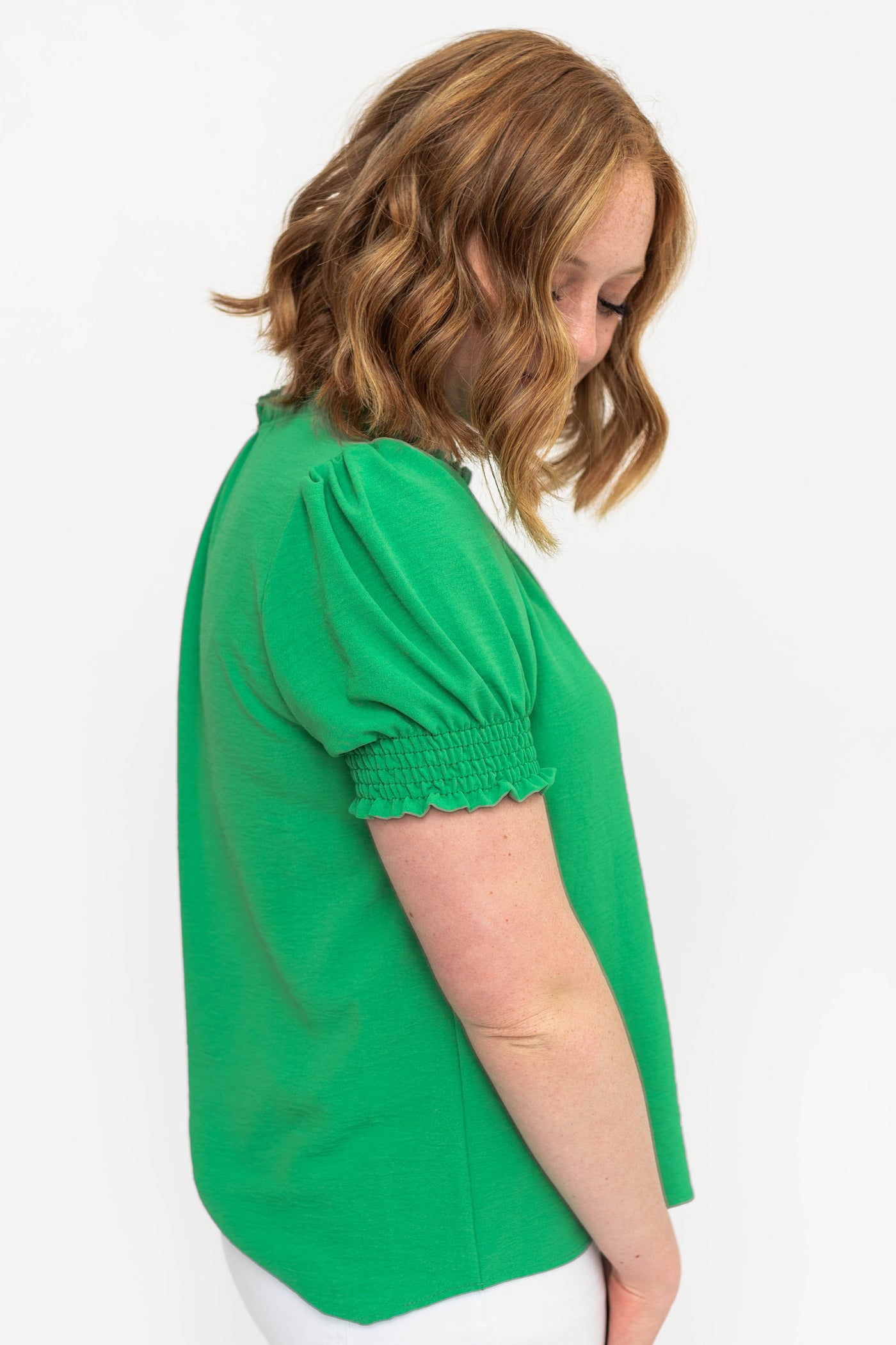 Side view of a kelly green top with puff short sleeves