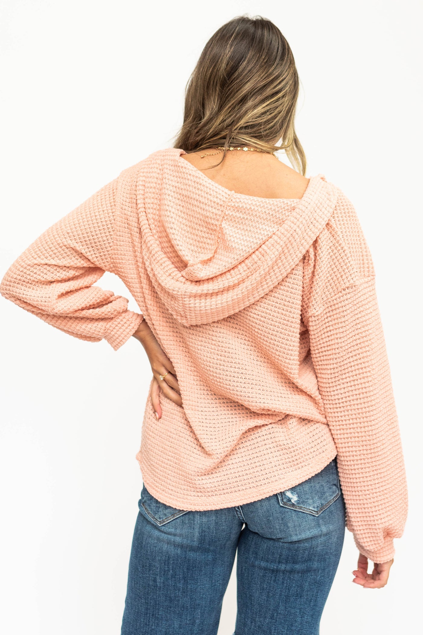 Back view of a peach long sleeve two button light weight hoddie sweater.