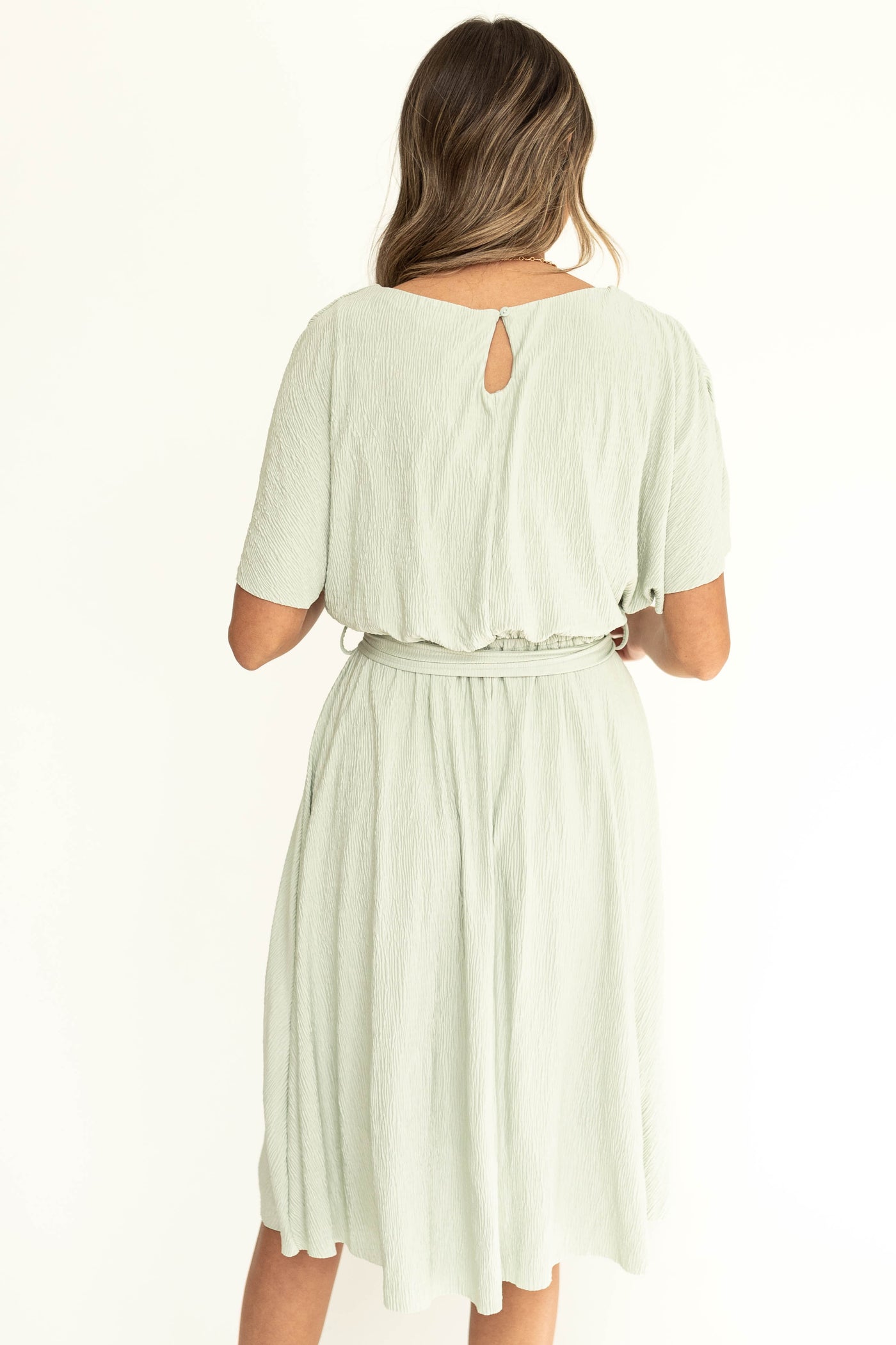 back view of a sage colored short sleeve dress that ties a waist 