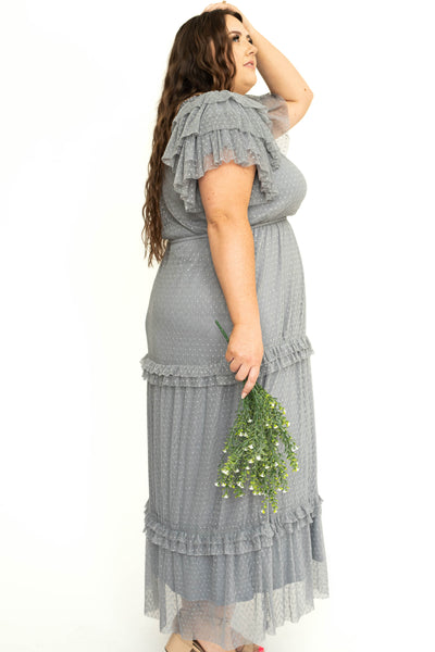 Side view of a plus size blue gray lace short sleeve dress with ruffles on sleeves and neck.