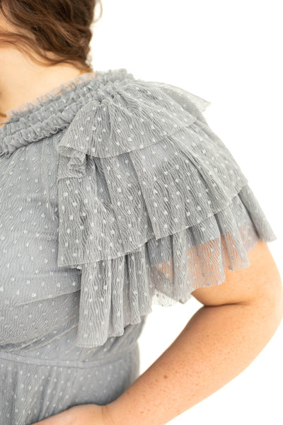 Sleeve view of a plus size blue gray lace short sleeve dress with ruffles on sleeves and neck.