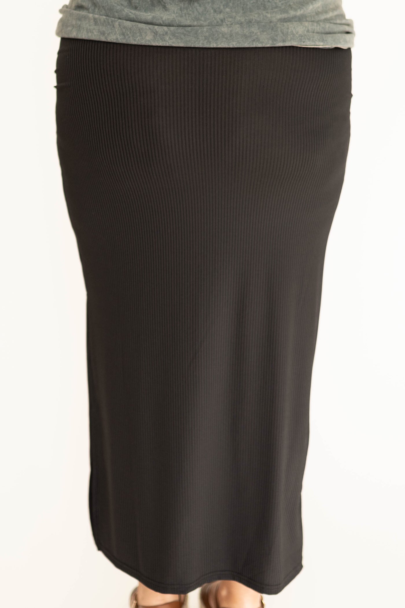 Back view of a plus size black fitted skirt with side slit. 