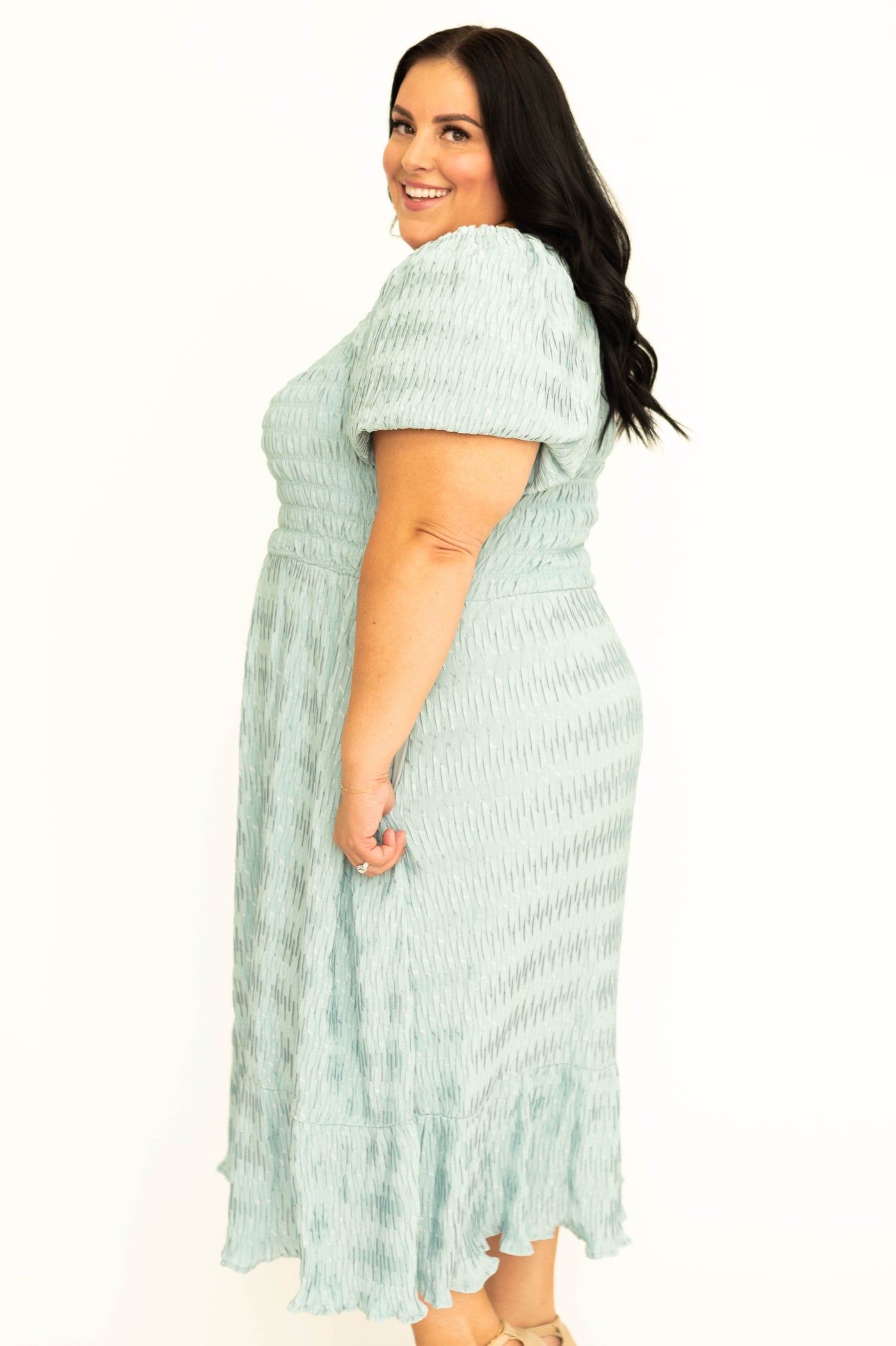 Side view of a plus size short sleeve seafoam dress with smocked bodice.